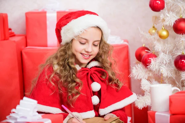 Child santa costume believe in miracle. Letter for santa. Wish list. Girl little kid hold pen and paper near christmas tree writing letter. I was good girl all year. Child write letter to santa claus — Stock Photo, Image