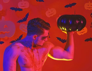 Yüzünde ve göğsünde kan olan adam kaslarını gösteriyor..