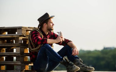 Harika bir hikaye. Kement ipli bir kovboy. Batı. Çiftlikte kareli gömlek. Batı kovboy portresi. Klasik tarz adam. Vahşi Batı eski kovboy. Vahşi batı rodeosu. Şapkalı düşünceli adam viski içiyor.