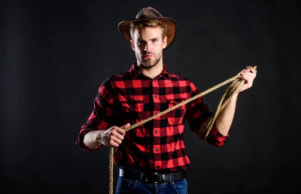 W Teksasie. Dzikie zachodnie rodeo. Człowiek w czarnym tle kapelusza. Zachodni portret kowboja. Człowiek w starym stylu. Kowboj z Dzikiego Zachodu. Kowboj z liną lasso. Zachodni. mężczyzna w kratkę koszula na ranczu — Zdjęcie stockowe