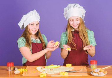 Özenle yapılan tatlı. Küçük çocuklar birlikte tatlı pişiriyor. Küçük kızlar mutfakta tatlı pişmiş pasta tatlı pişirme. Sevimli aşçılar cutout kurabiye pişmiş tatlı hazırlanması