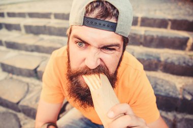 Urban lifestyle nutrition. Junk food. Carefree hipster eat junk food while sit stairs. Guy eating hot dog. Snack for good mood. Unleashed appetite. Street food concept. Man bearded eat tasty sausage clipart