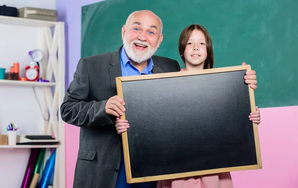 A Better Way Found. mature teacher and happy pupil girl. small girl with man tutor study. blackboard for information and announcement. Copy space. school classroom. empty chalk board. School sales — Stock Photo, Image