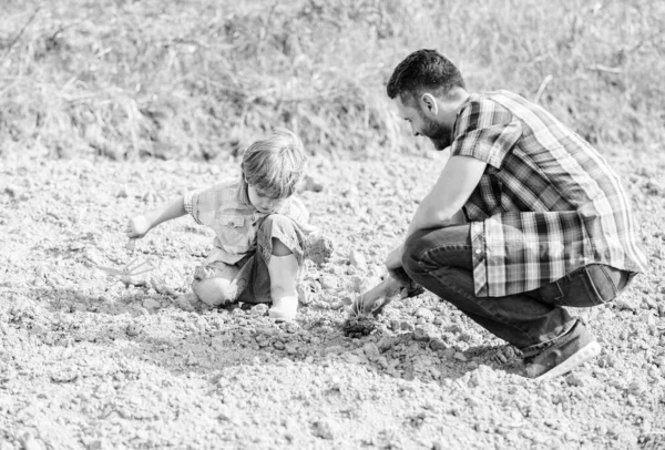 Μικρό αγόρι παιδί βοηθήσει τον πατέρα στη γεωργία. νέα ζωή. εδάφη και τα λιπάσματα. μέρα της ευτυχης γης. Υποστηρικτής του περιβάλλοντος. πατέρας και γιος φυτεύουν λουλούδια στο έδαφος. πλούσιο φυσικό χώμα. Οικολογική φάρμα. ημέρα της γης — Φωτογραφία Αρχείου
