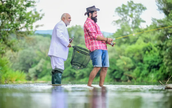 Buen pescador respeta los recursos naturales. El pescado nunca debe desperdiciarse. Si la captura de peces que está bajo liberación legal que rápidamente. Licencia de pesca estatal. Hombres pescando juntos. Pescado con amigo. Ocio masculino —  Fotos de Stock