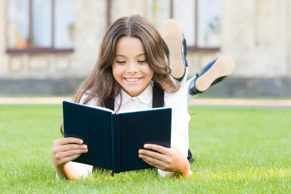Kennis is meer dan informatie. Gelukkig klein meisje lees boek op groen gras. Schattig klein schoolkind krijgt kennis van lezen. Kennisdag of 1 september. Test je schoolkennis — Stockfoto