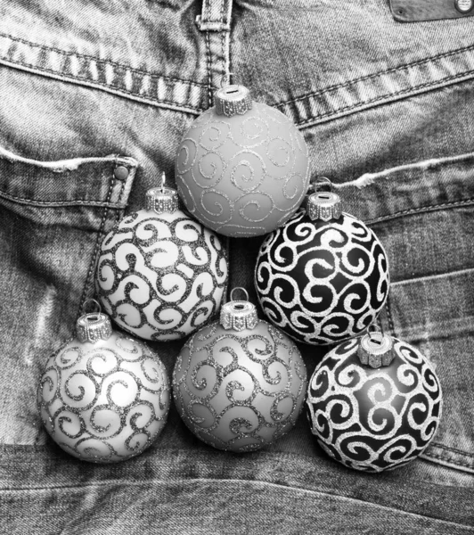 Christmas ornaments or decorations on denim pants background. Christmas decorations concept. Pick colorful decorations. Modern christmas decor. Balls with glitter and shimmering decorative ornaments