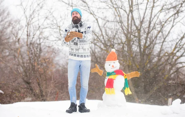 Have fun frosty winter day. Let it snow. Christmas holidays. Active lifestyle. Man bearded hipster cute knitted hat play with snow outdoors. Snow games. Leisure on fresh air. Snowman concept