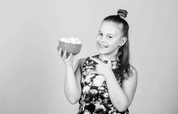 Niña con el pelo largo le gustan los dulces y golosinas. Caloría y dieta. Chico hambriento. Desafío malvavisco. Chica sonriente cara sostener tazón con malvaviscos dulces en fondo beige mano. Concepto de diente dulce — Foto de Stock