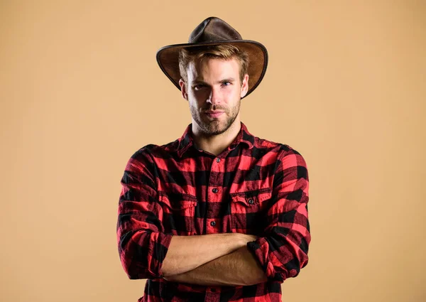 Exemplo de verdadeira masculinidade. Um cowboy a usar chapéu. Cowboy americano. A vida ocidental. Homem unshaven cowboy bege fundo. Um tipo sem barba de chapéu de cowboy. Bonito macho barbudo. Padrão de beleza — Fotografia de Stock