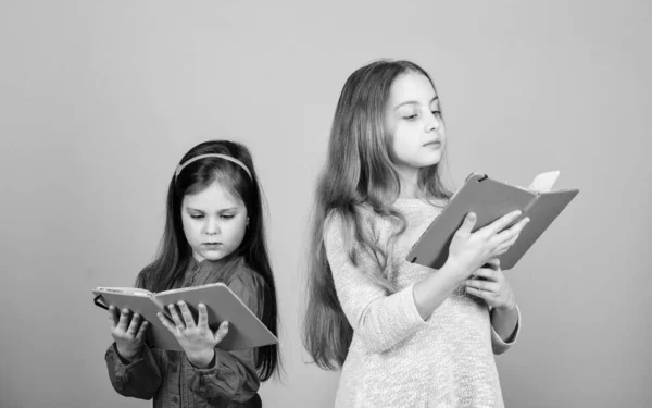 As irmãs escolhem livros para ler juntas. Meninas adoráveis amam livros. Abrir portas através da alfabetização. Crianças meninas com livros ou blocos de notas. Educação e literatura infantil. Conto de fadas favorito. De volta à escola — Fotografia de Stock