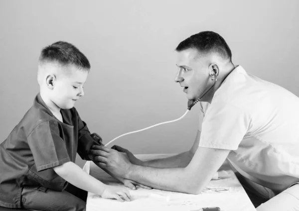 O pediatra cuidadoso verifica a saúde da criança. Exame médico. Trabalhador hospitalar. Serviço médico. Homem médico sentar ferramentas médicas mesa examinando menino paciente. Saúde. Conceito de pediatra — Fotografia de Stock