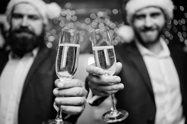 Gli uomini d'affari bevono champagne alla festa. I colleghi festeggiano l'anno nuovo. Gli uomini vestiti formali e cappelli di Babbo Natale tengono bicchieri di champagne. Concetto di salute. Festa aziendale di Capodanno. Festa con champagne — Foto Stock
