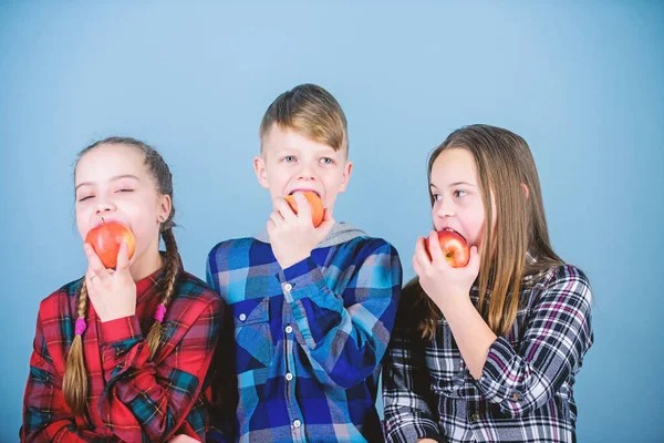 An apple a day keeps the doctor away. Little children biting red apples. Small group of children eating apples together. Cute children enjoying tasty juicy apples