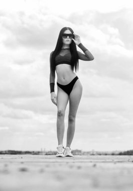 İnce bel ve uzun bacaklar. Sportif kız mükemmel vücut. Spa tesisi. Yaz vücudu. Şehvetini ifade etmekte özgür hissediyorum. Kız çekici seksi vücut gökyüzü arka plan poz. Kadın güneş gözlüğü ve bikini giymek