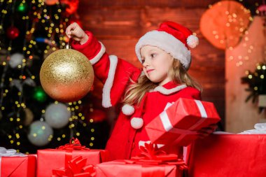Şenlikli bir atmosfer için bayram süsü getirdim. Elinde Noel süsleri tutan küçük bir çocuk. Küçük kız süs topu süslemesine bakıyor. Xmas iç dekorasyonunda tatlı bir çocuk.