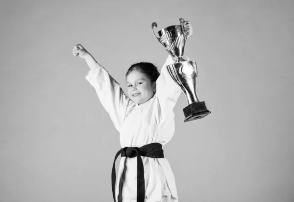 Sport success. Training to be the best. small girl with champion cup. martial arts. practicing Kung Fu. happy childhood. winner little girl in gi sportswear. knockout. energy and activity for kids — Stock Photo, Image