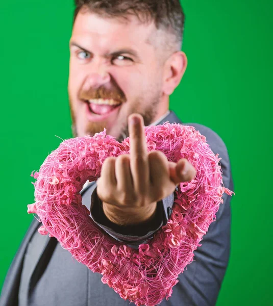 Hate you. Disappointed love valentines day. Romantic macho show middle finger gesture. Happy valentines day. Hipster hold heart symbol love. Man formal suit celebrate valentines day green background