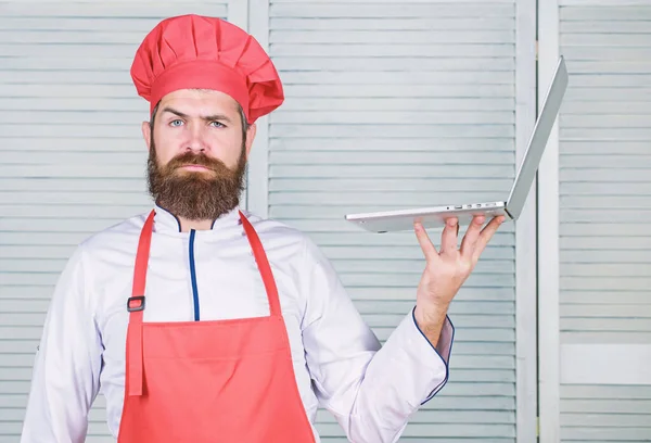 Lieferservice. Chef-Laptop in der Küche. Kochschule. Hipster in Hut und Schürze kaufen Produkte online. Online einkaufen. Mann Koch Suche online Zutaten Kochen von Lebensmitteln. Lebensmittelgeschäft online — Stockfoto