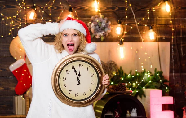 Cheerful woman.. Be happy. Time to celebrate. girl in red santa claus hat. Midnight. happy new year. christmas preparation. winter holidays. Its time for christmas. xmas mood. Woman wi clock