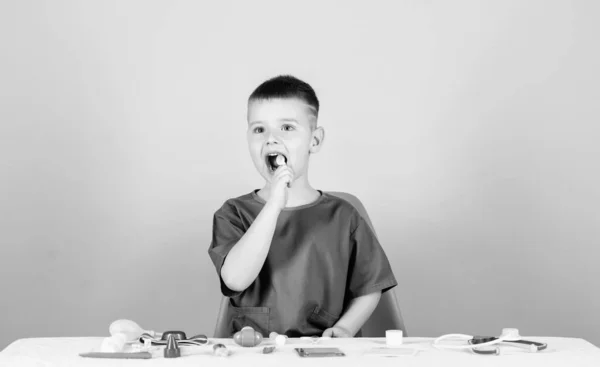 Niño lindo niño futuro médico carrera. Vida sana. El niño pequeño médico se sienta en la mesa con estetoscopio y herramientas médicas. Concepto de medicina. Salud. Examen médico. Educación médica. Jugar juego — Foto de Stock