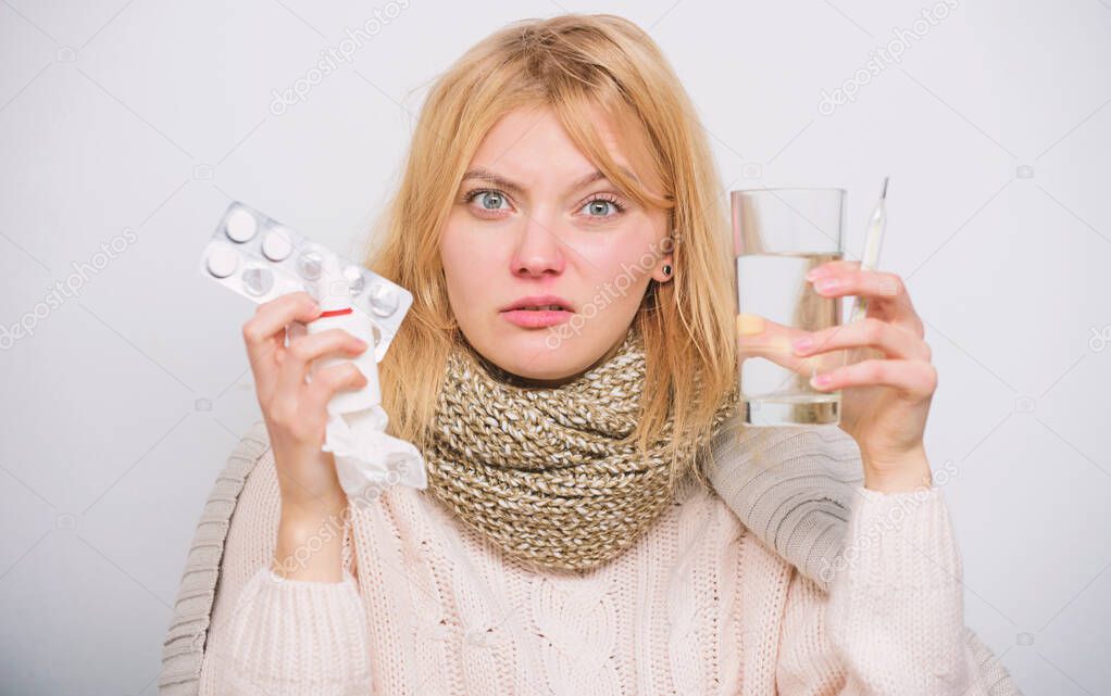 Following drug dosage regime. Sick girl taking anti cold pills. Ill woman treating symptoms caused by cold or flu. Unhealthy woman holding pills and water glass. Medication and increased fluid intake