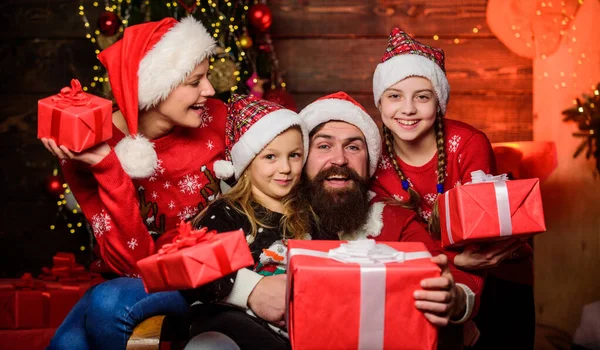 Sharing memories. Happy family celebrate new year and Christmas. open xmas present. gifts from santa. santa father at decorated tree. small girls sisters with parents. cheerful mother love children