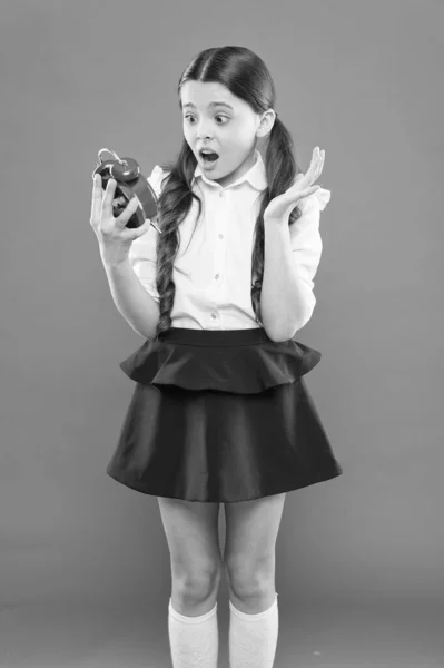 Adormeceu e está atrasado para a escola. Hora de ir para a escola. Dia do conhecimento. Hora da escola. Menina feliz espera despertador contando para a hora do almoço. horário diário de rotina. estudante e retro despertador relógio — Fotografia de Stock