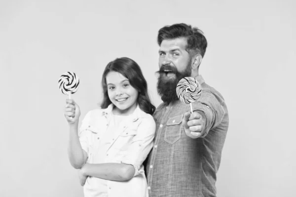 Lieve kindertijd. Meisje kind en papa houden kleurrijke lollies. Snoep en traktaties concept. Dochter en vader eten zoete snoepjes. Zoete dessert. Bearded hipster goede papa voor schattige dochter — Stockfoto