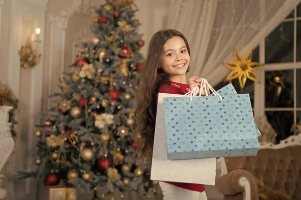 子供女の子クリスマス プレゼントが好きです。クリスマス前に朝。年末年始。買い物袋を持つ少女。クリスマス。子供では、休暇をお楽しみください。明けましておめでとう。クリスマスに小さな幸せな女の子。メリークリスマス — ストック写真