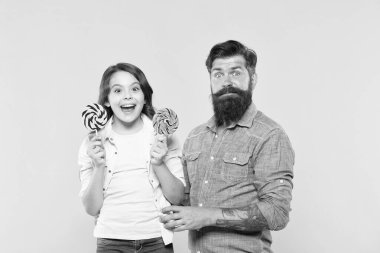 Sevgili insanlarla tatlılar paylaşmak. Kız ve baba tatlı şekerler yemek. Tatlı çocukluk. Kız çocuk ve baba renkli lolipop tutun. Tatlı tatlısı. Sevimli kızı için sakallı hipster iyi baba