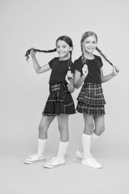 Eğlenceli çocuklar. Birlikte mutlu. Okul arkadaşları birlikte eğleniyor. Neşeli arkadaşlar. Sevimli küçük kızlar sarı arka plan gülümseyen. Aynı kıyafetleri giyen mutlu küçük kızlar. Arkadaşlığa zevk olan arkadaşlar