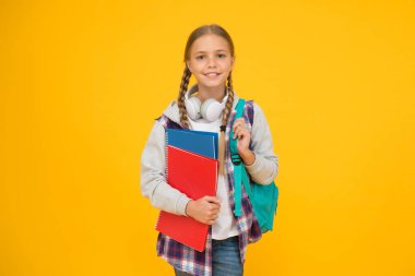 Merhaba okul. Mutlu kız sarı arka planda okula hazır. Küçük çocuk kitapları ve okul çantasını tutuyor. Küçük çocuk sonbaharda okula geri dönüyor. Eğitim ve bilgi