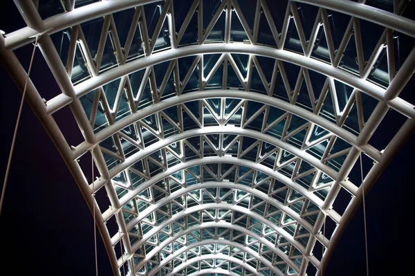 Αρχιτεκτονικό στοιχείο της γέφυρας σκοτεινό φόντο ουρανό νύχτα. Χαλύβδινη κατασκευή φωτίζεται πολλά φώτα. Αρχιτεκτονική έννοια. Γέφυρα στην Τιφλίδα. Γυάλινα καπάκια λαμπυρίζουν. Σύγχρονη γέφυρα σχεδιασμού — Φωτογραφία Αρχείου