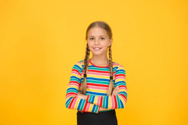 Look casual ma carino. Ragazza adorabile con moda sguardo sfondo giallo. Bambino piccolo con occhiata di bellezza di acconciatura intrecciata lunga. Vogue sguardo di piccolo modello di moda — Foto Stock