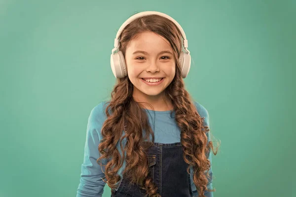 현대적이고 세련된. 파란색 배경에 현대 음악을 즐기는 행복한 어린 아이. 현대 노래를 듣고 세련된 헤드폰에 작은 소녀. 즐거움과 연구를 위해 현대 기술을 사용 — 스톡 사진