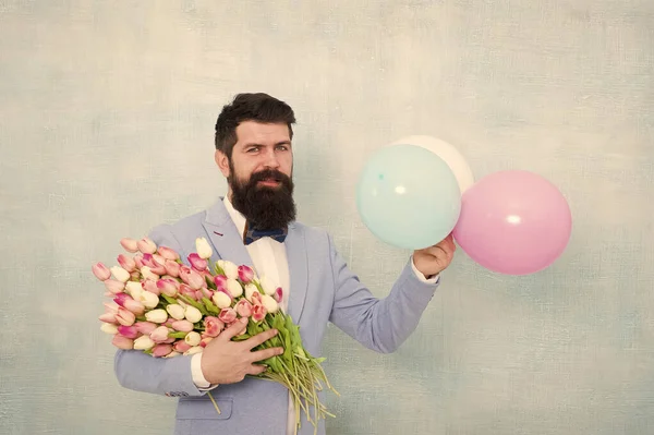 Para alguien especial. Hombre barbudo caballero traje pajarita celebrar globos de aire y ramo. Caballero haciendo una sorpresa romántica para ella. Entrega de flores. Una cita romántica entre caballeros. Saludos de cumpleaños — Foto de Stock