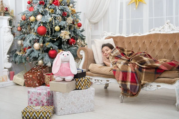 Believe in miracles. Magical moment. Christmas night. Happy new year. Family holiday. Christmas tree and presents. Dreaming about gifts. Little girl sleep couch near christmas tree classic interior