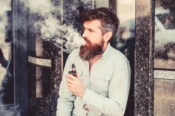 Concepto de hábitos. hombre fumando cigarrillo electrónico. hipster hombre mantenga el dispositivo de vapeo. Hipster maduro con barba. Seguridad y adicción a la salud. inhalando vapor. Barbudo brutal macho fumar cigarrillo electrónico — Foto de Stock