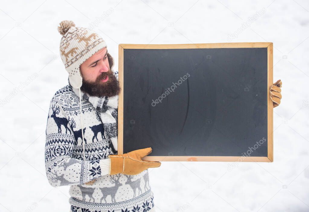 information. winter holiday. Party here. man advertising board. Copy space. happy hipster with blackboard. ski and sledge. bearded man in warm clothes. Happy new year. winter season. Christmas sales
