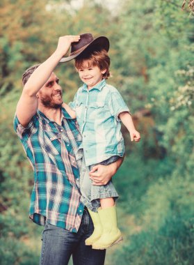 Çocuk eğleniyor kovboy baba. Çiftlik ailesi. Ebeveyn çiftliğinde tatiller. Büyüyen sevimli kovboy. Hafta sonu çiftlikte. Küçük çocuk ve baba doğa arka plan. Macera ruhu. Bahçede küçük yardımcı