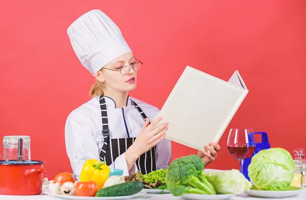 Koken en serveren gezond vegetarisch menu. Mooie vrouwelijke kok lezen menukaart bij keuken tafel. Schattig vrouw leren restaurant menu voor een dag. Menu eten en drinken lijst — Stockfoto