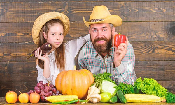 Family farm festival concept. Family father farmer gardener with daughter near harvest vegetables. Man bearded rustic farmer with kid. Countryside family lifestyle. Farm market with fall harvest