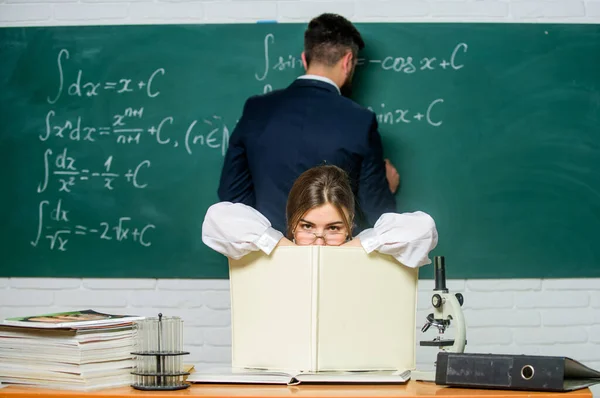 Studeren in de klas zoals gewoonlijk. Mooie klas meester die les geeft op school. Slimme leraar met klasregister zit aan tafel terwijl student het schrijven van formule op schoolbord. Laboratoriumklasse — Stockfoto