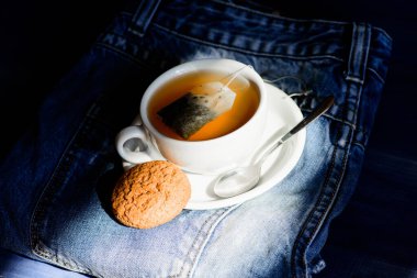 Bardak dolu çay, yakın çekim. Bitki yeşili ya da siyah yaprak. Çay demleyen seramik bardak. İlham ve huzurlu bir ruh hali. Papatya çayı içiyorum. Kupa kupası sıcak çay ve yulaflı kurabiye. Hızlı atıştırma konsepti