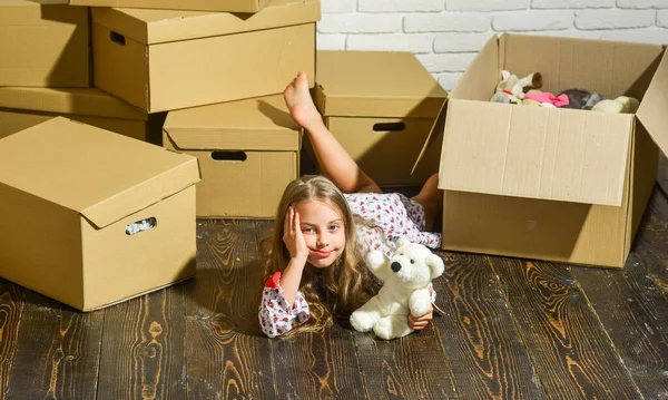 The Epicenter of Luxury and Convenience. Cardboard boxes - moving to new house. happy little girl with toy. playing into new home. new apartment. purchase of new habitation. happy child cardboard box — Stock Photo, Image