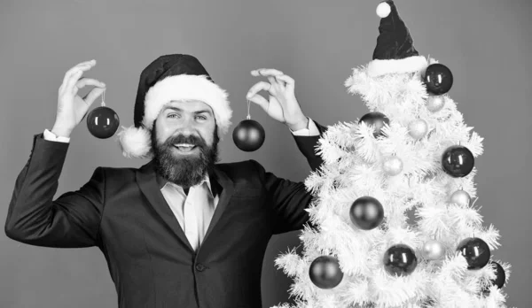 Noel atmosfer etrafında yayılmış. Tatil eğlence için demek istedim. Adam giyim resmi takım elbise ve santa şapka sakallı. İşadamı Noel kutlamaları katılın. Noel Baba Noel top dekorasyon tutun. Mutlu Noeller — Stok fotoğraf