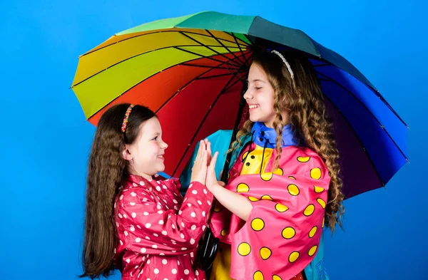 Joyeux enfants hipster, fraternité. protection contre la pluie. Arc en ciel. liens familiaux. Des petites filles en imperméable. joyeuses petites filles avec parapluie coloré. mode d'automne. matinée sans soucis — Photo