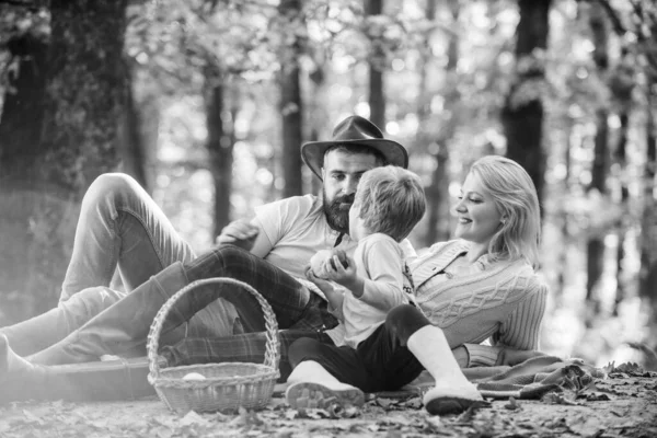 Sonniges Wetter. Gesunde Ernährung. Familienpicknick. Mutter, Cowboy-Vater lieben ihren kleinen Jungen. glücklicher Sohn mit Eltern entspannen im Herbstwald. Frühlingsstimmung. glücklicher Familientag. Leckeres Essen genießen — Stockfoto