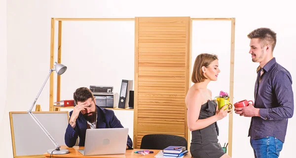 Employee break. Business partners enjoying conversation in lunch break while colleague working in background. Two coworkers having tea or coffee break. Young managers talking during work break